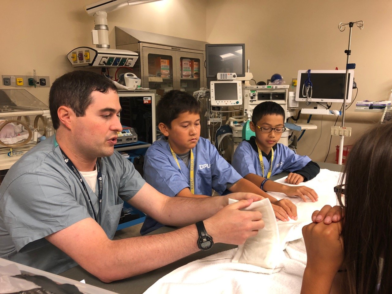 Dr. Eyre explains medical simulation to two male EXLPO students