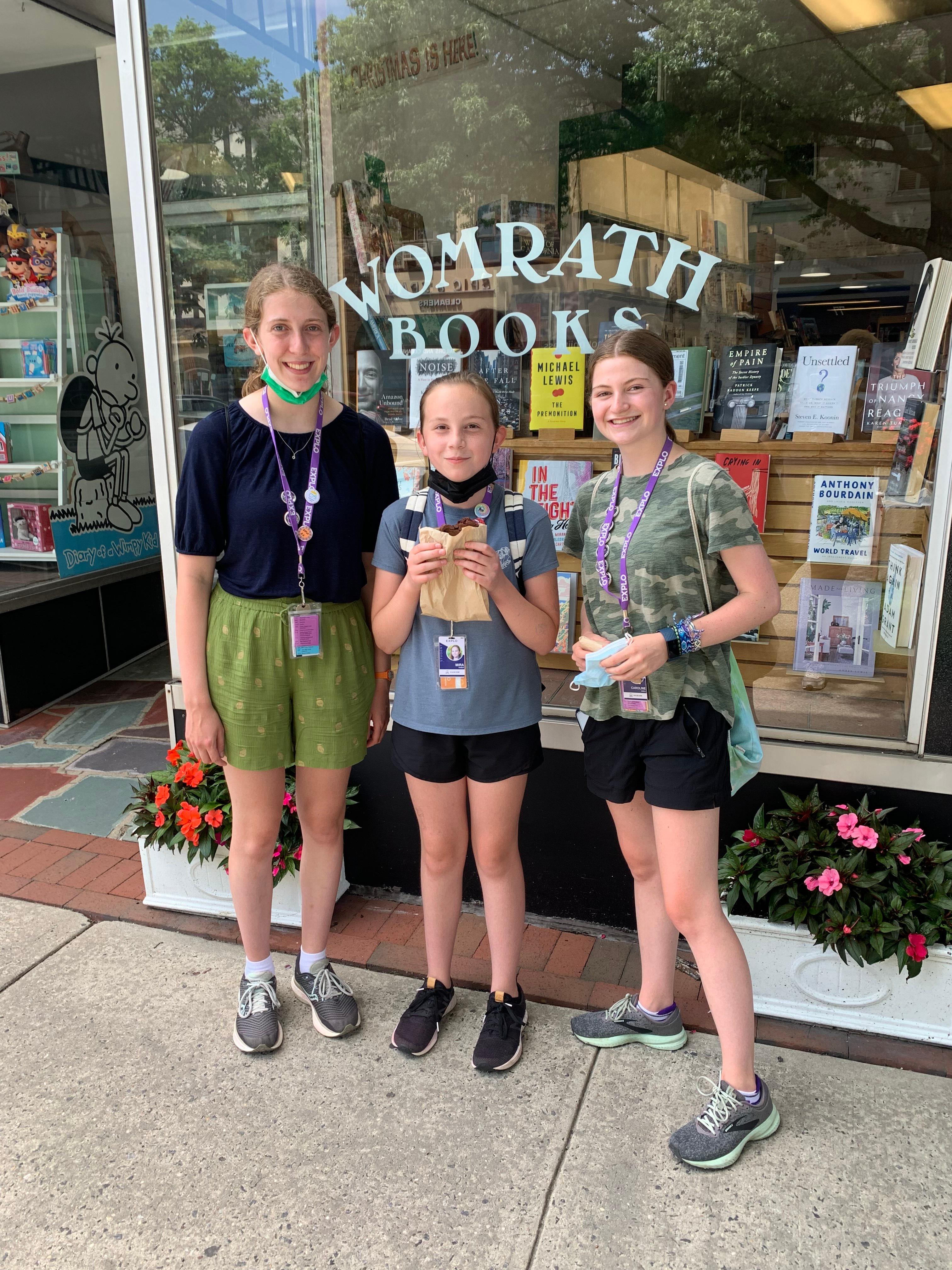 Three female EXPLO students stand in front of Womrath Books, a book shop in Bronxville, NY.